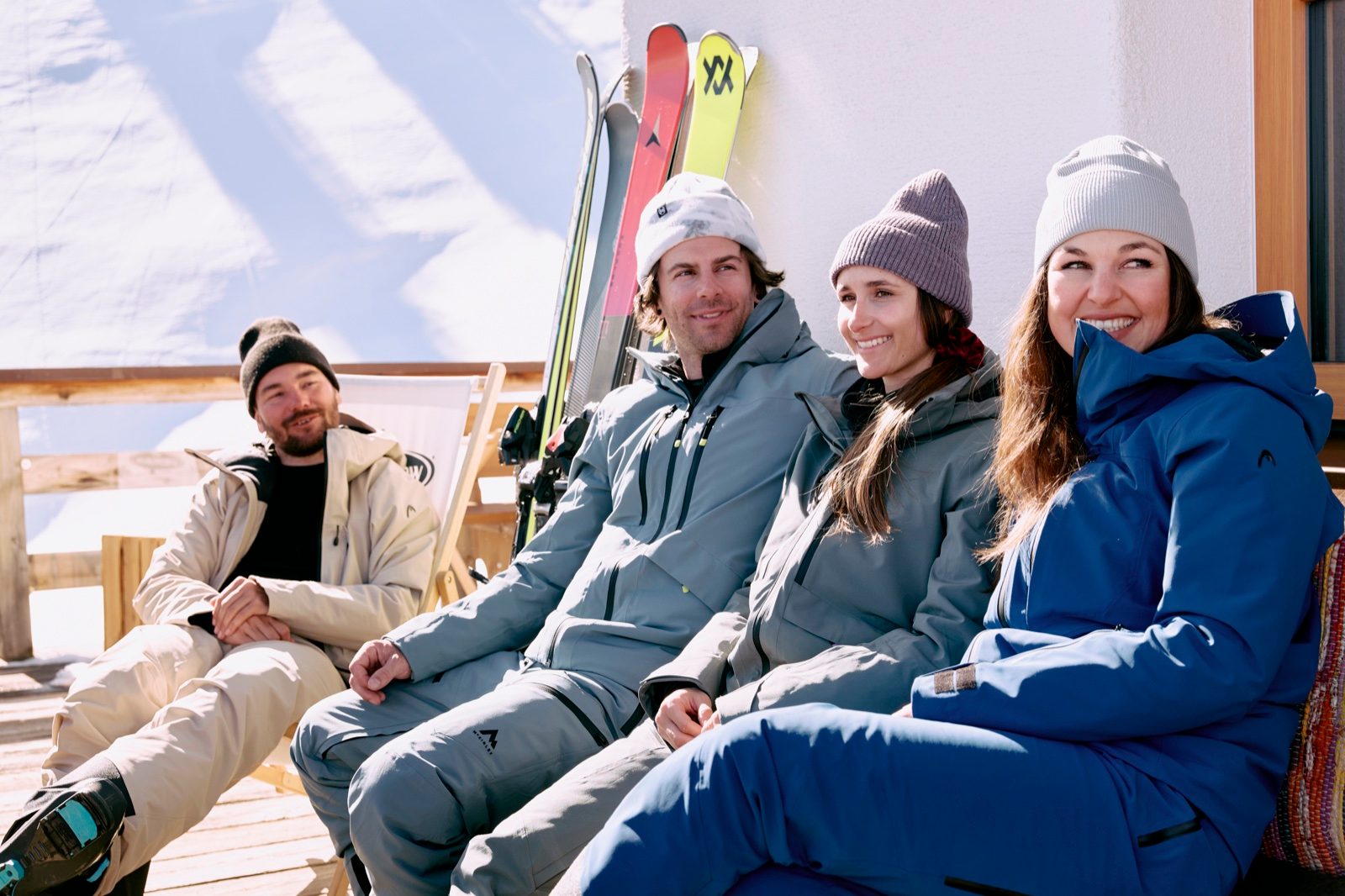Eine Vier-Personen-Crew in Premium-Skioutfits genießt eine sonnige Pause, ihre Skis aufgereiht im Hintergrund — Kappl im Paznaun