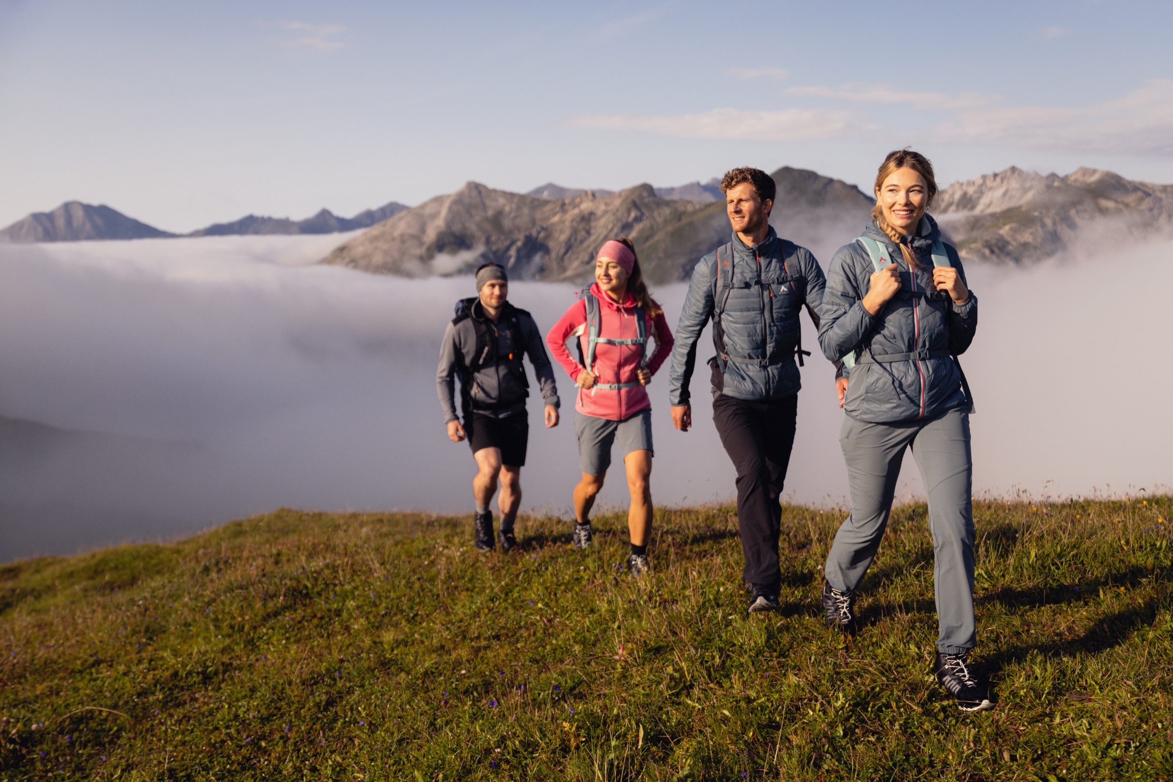 Vier Wanderer steigen im Morgenlicht über einen Bergkamm über Kappl, im Tal ein Wolkenmeer