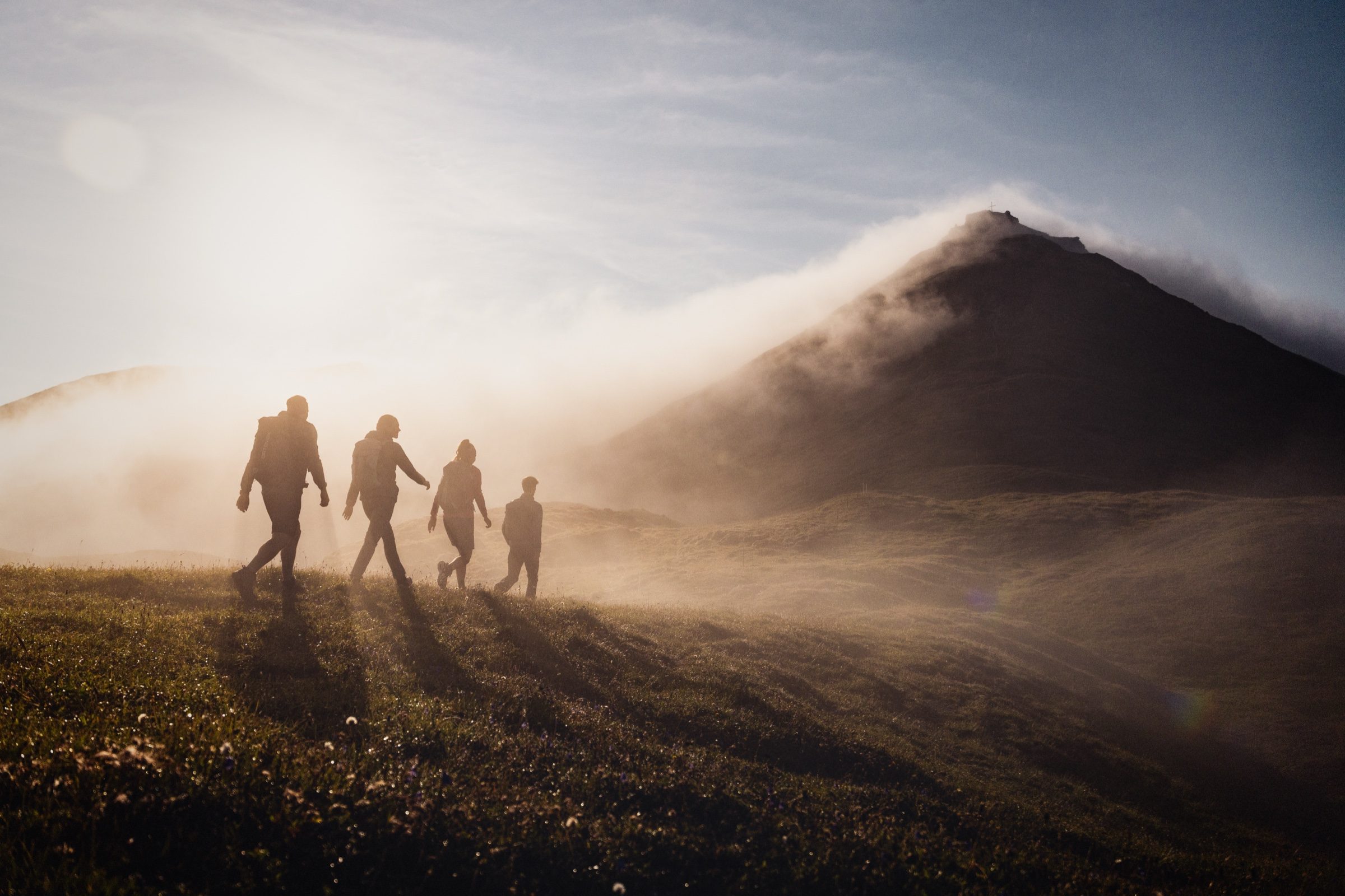 Wandergruppe als Silhouetten auf einem Grat im Morgennebel über Kappl im Paznaun