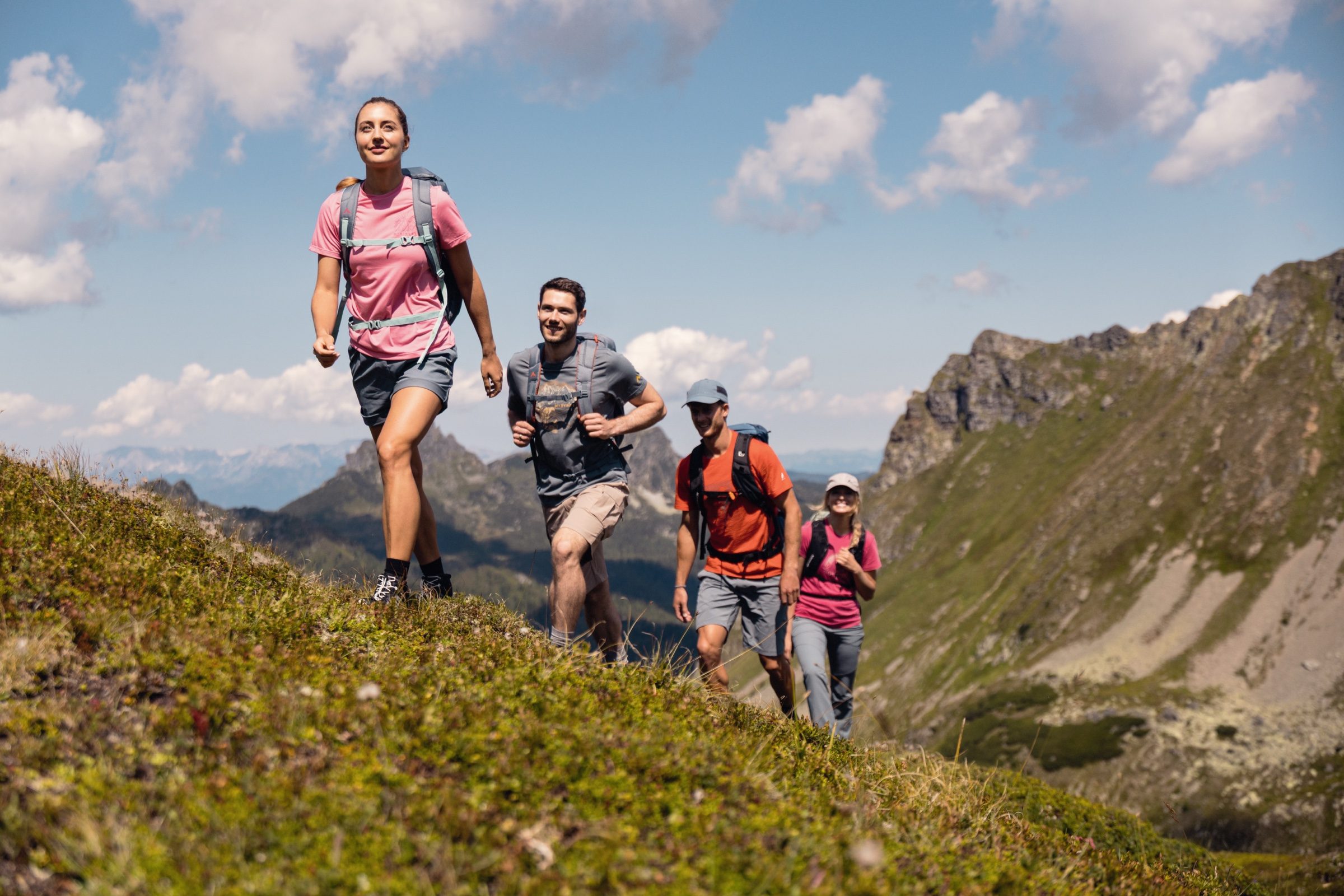 Wandergruppe steigt an einem sonnigen Sommertag über einen Grat über Kappl ab, dahinter ein markanter Gipfel