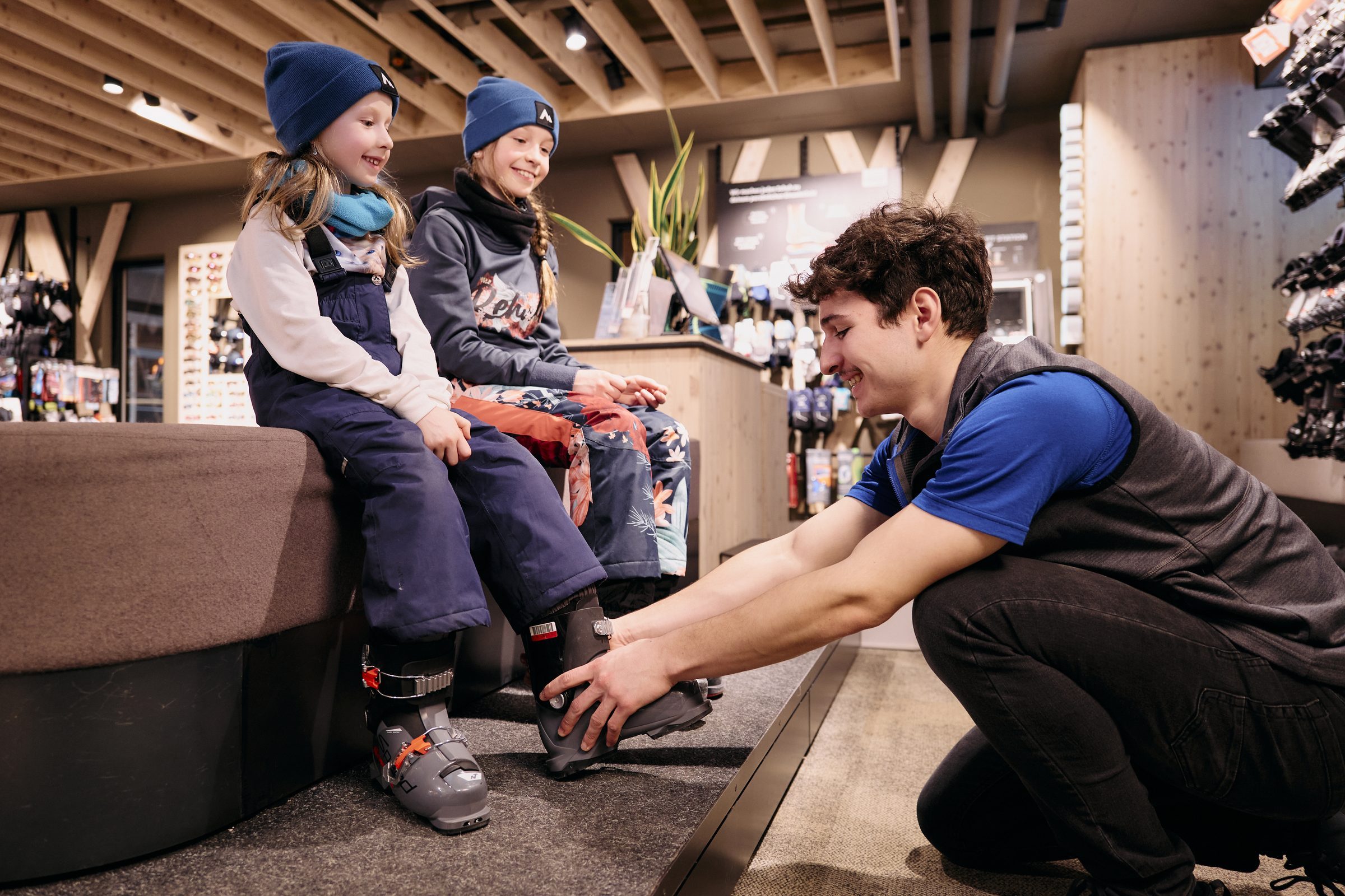 Skischuh-Anprobe im Shop — Mitarbeiter passt zwei Kindern die Schuhe an