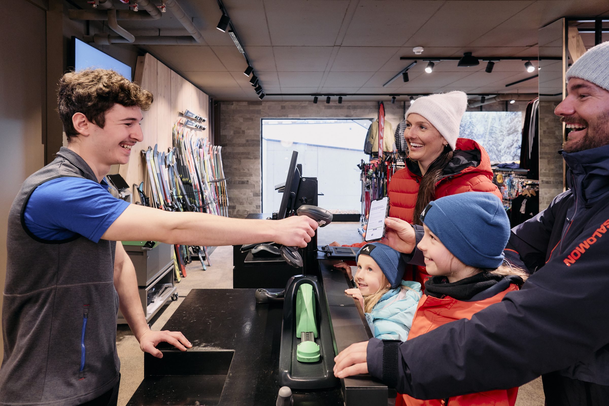 An der Theke im INTERSPORT-Shop — Skiwand und Wintermode im Hintergrund